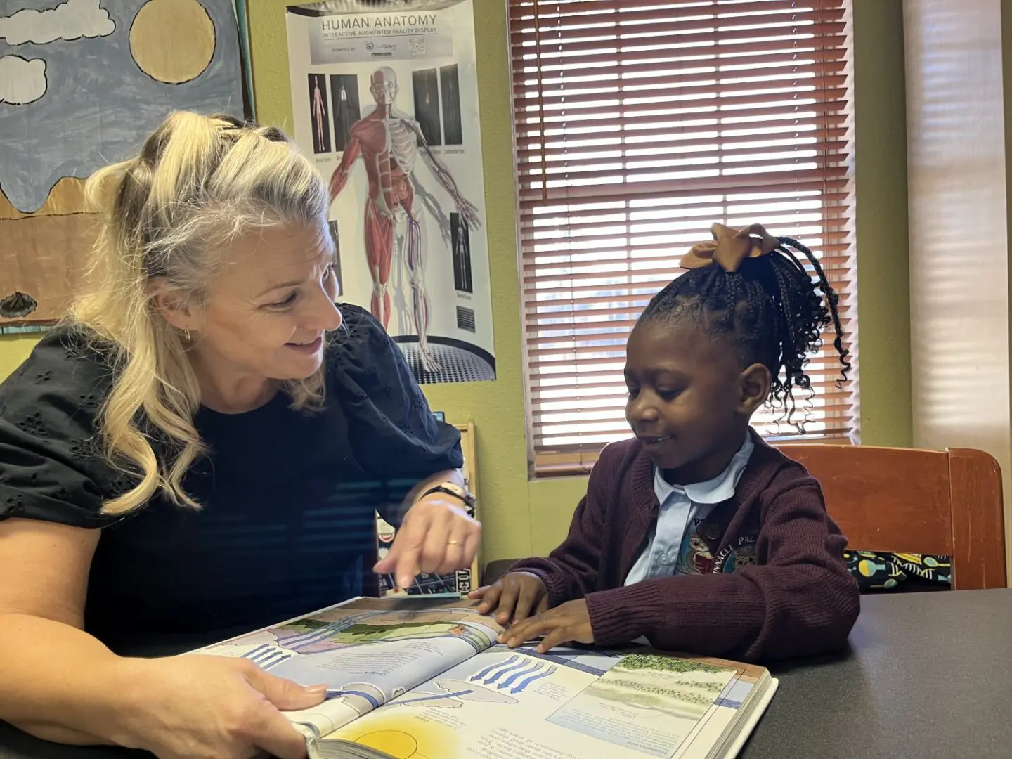 A woman and child are looking at a book.