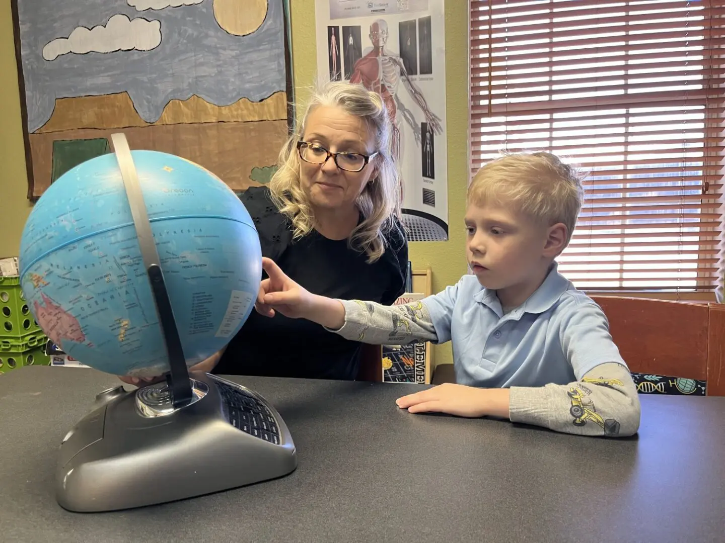 A woman and boy looking at an object on the table.