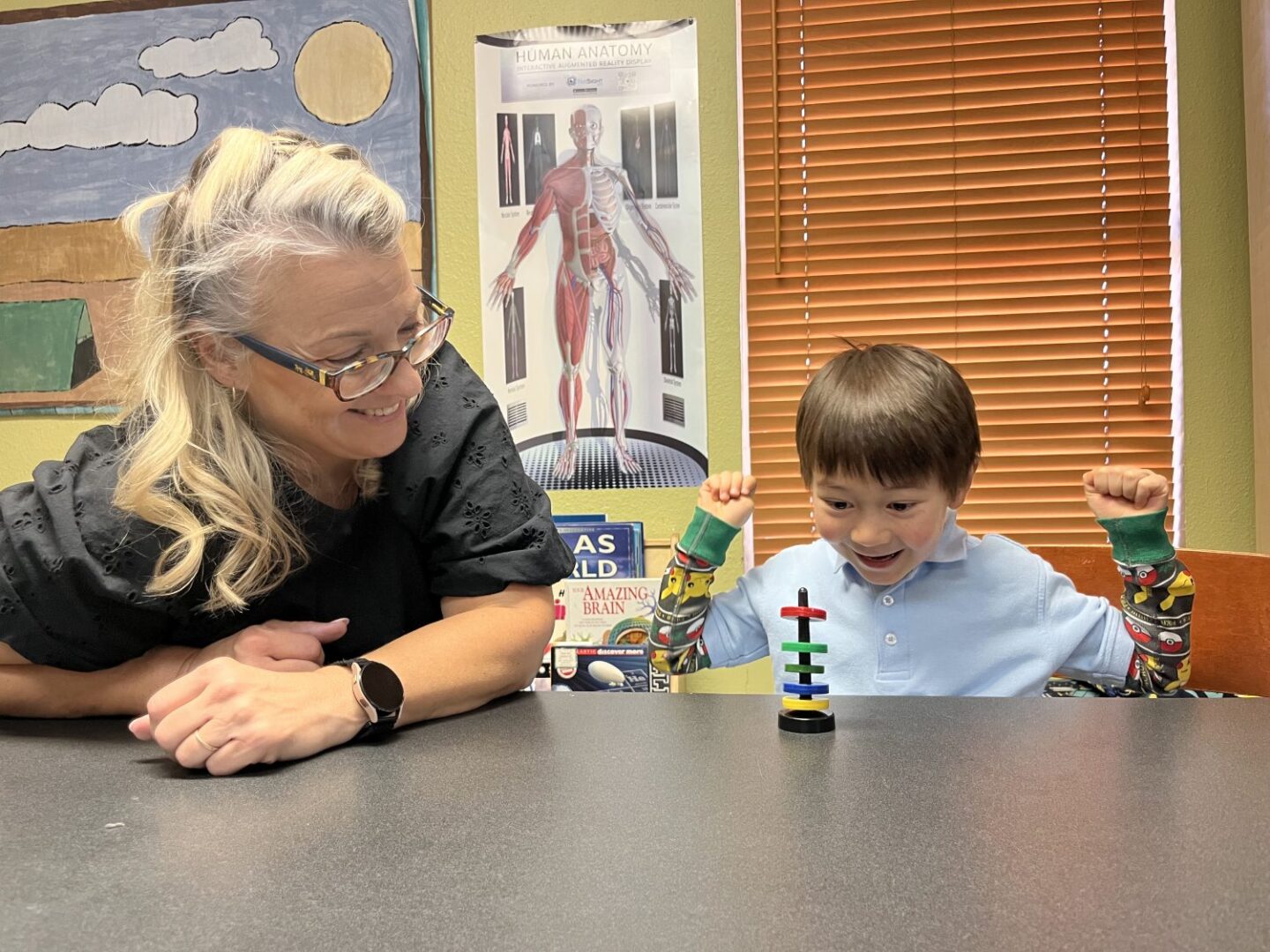 A woman and boy sitting at table with toy.