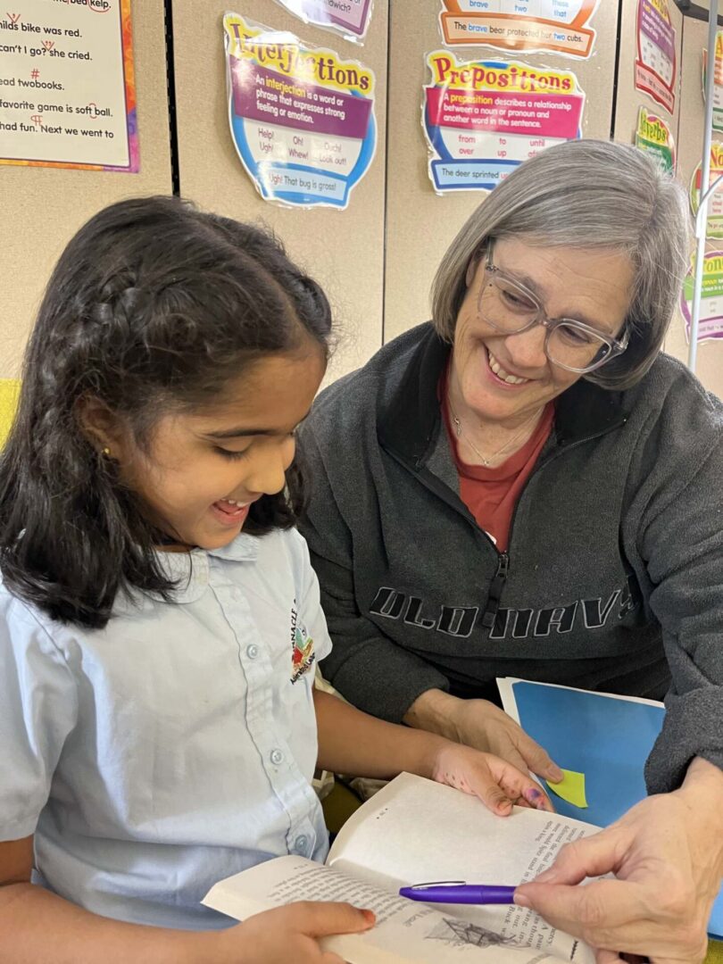 A woman and girl are looking at something on the book.